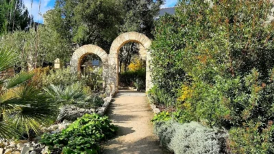 Allée ensoleillée avec arches de pierre dans un jardin près de Quimper, idéale pour une balade entre nature et patrimoine en Cornouaille