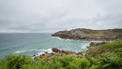 Paysage sauvage du Cap Sizun avec falaises rocheuses, maison isolée et océan Atlantique, un site incontournable de l’Ouest Cornouaille